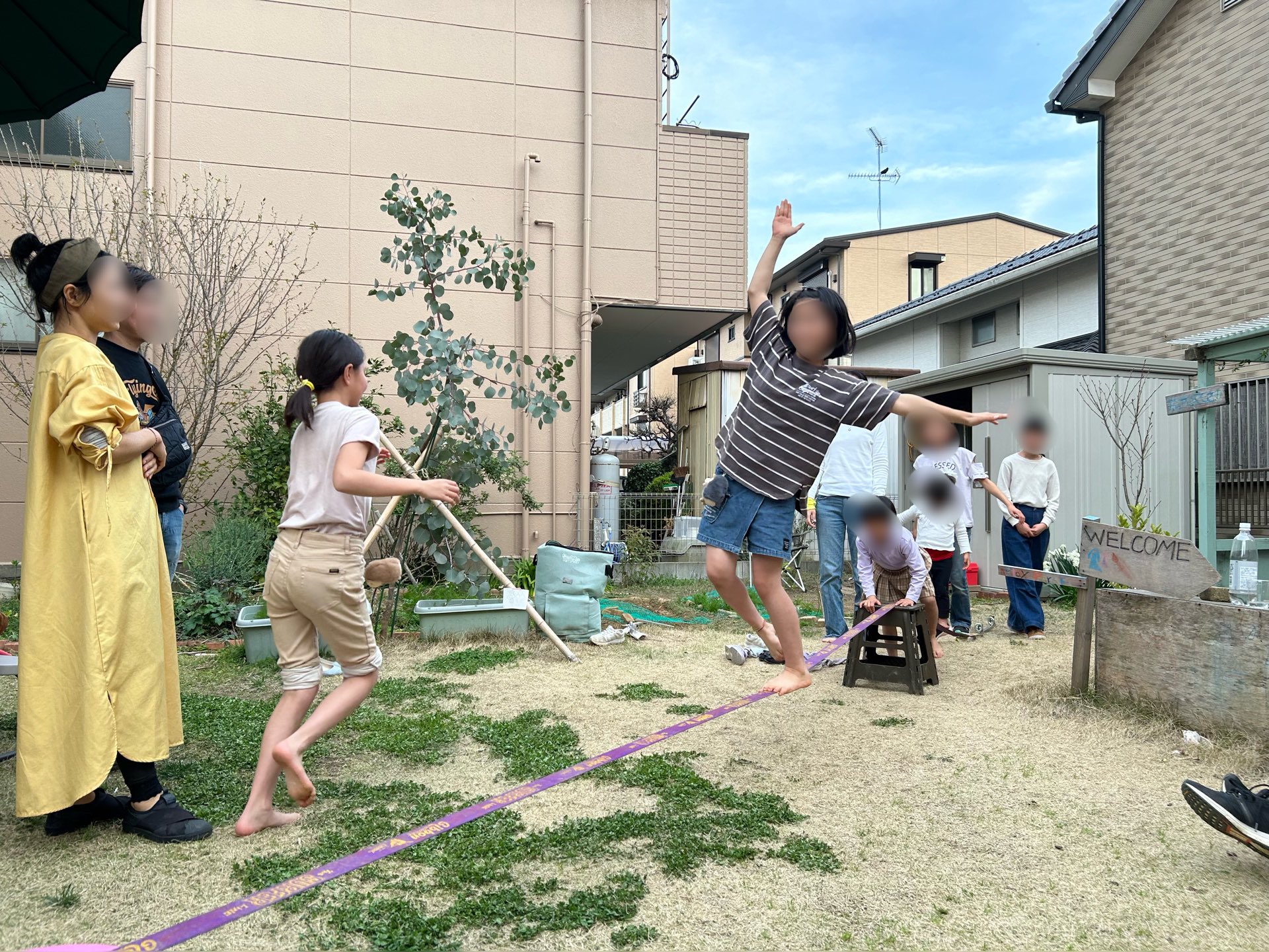 低く張ったスラックラインの上でバランスをとる参加者と、見守る人たち